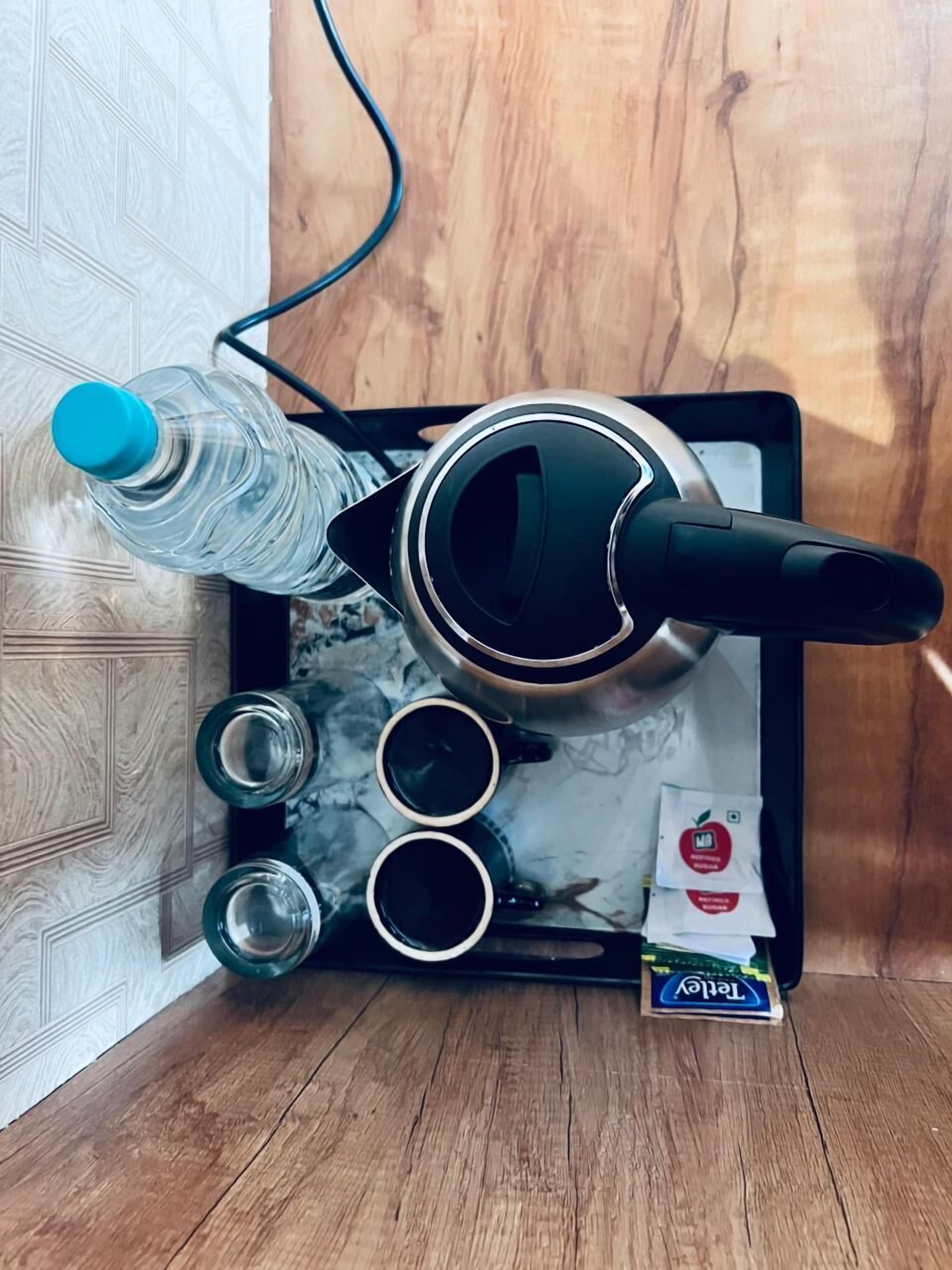 A kitchen setup with a kettle, water bottle, and cups on a tray.