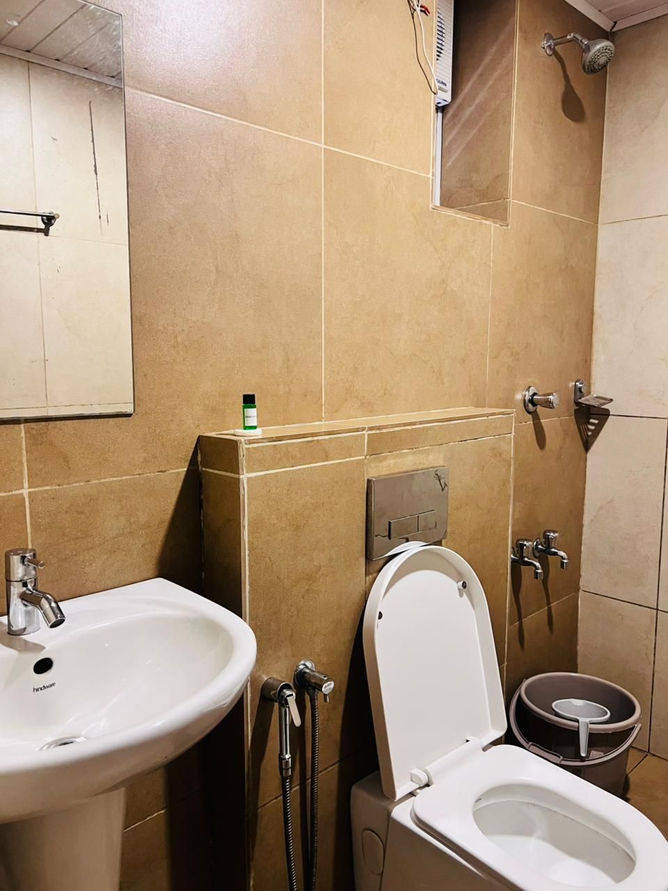 A bathroom with a sink, toilet, shower, and a mirror.