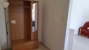 Habitació amb un armari de fusta, una làmpada de peu i un sofà vermell.