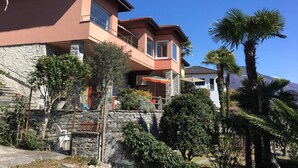 Une maison à deux étages avec une façade en pierre, un balcon et un mur en pierre.