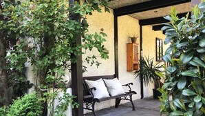 Ein überdachter Patio-Bereich mit einer Bank und Topfpflanzen.