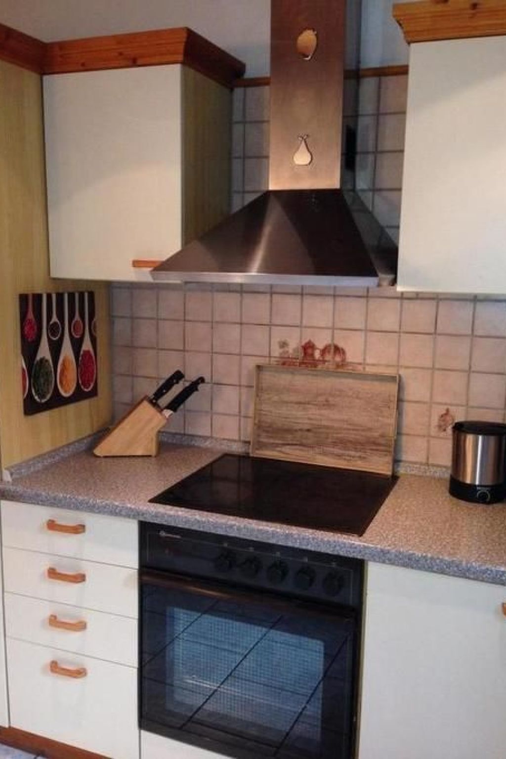 Una cocina con estufa, horno y tabla de cortar de madera sobre la encimera.
