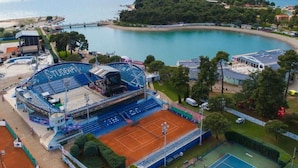 A tennis court with a seating area and a view of the sea. - Große Wohnung in Umag mit Terrasse und Grill by Interhome (Umag)