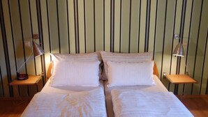 Een tweepersoonsbed met witte beddengoed, twee nachtkastjes en twee lampen.