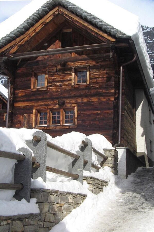 Eine Holzhütte mit Steinunterbau, umgeben von Schnee.