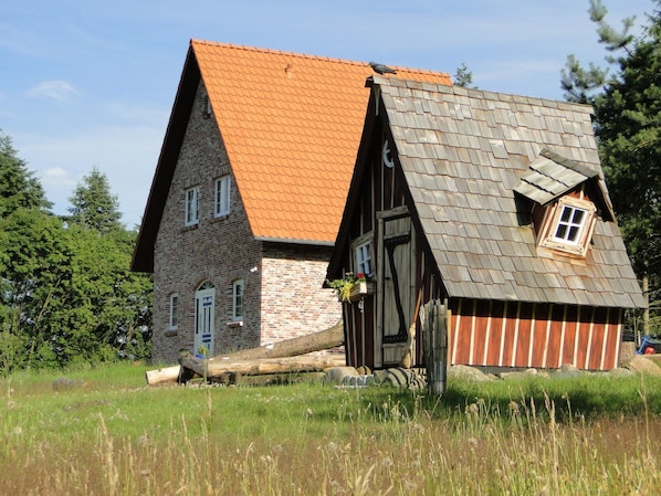 Perinteinen talo, jossa on kalteva katto, puuovi ja ikkuna.