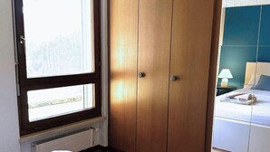 Un dormitorio con un armario grande, una ventana y una cama con una mesita de noche.