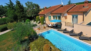 Ein zweistöckiges Haus mit Swimmingpool, Sitzgelegenheit im Freien und einem Garten.