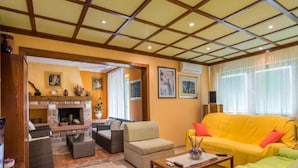 Ein Wohnzimmer mit Kamin, einem gelben Sofa und Korbmöbeln.