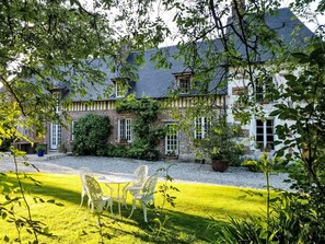 Une maison traditionnelle avec une façade en briques, des fondations en pierre et une pelouse bien entretenue.
