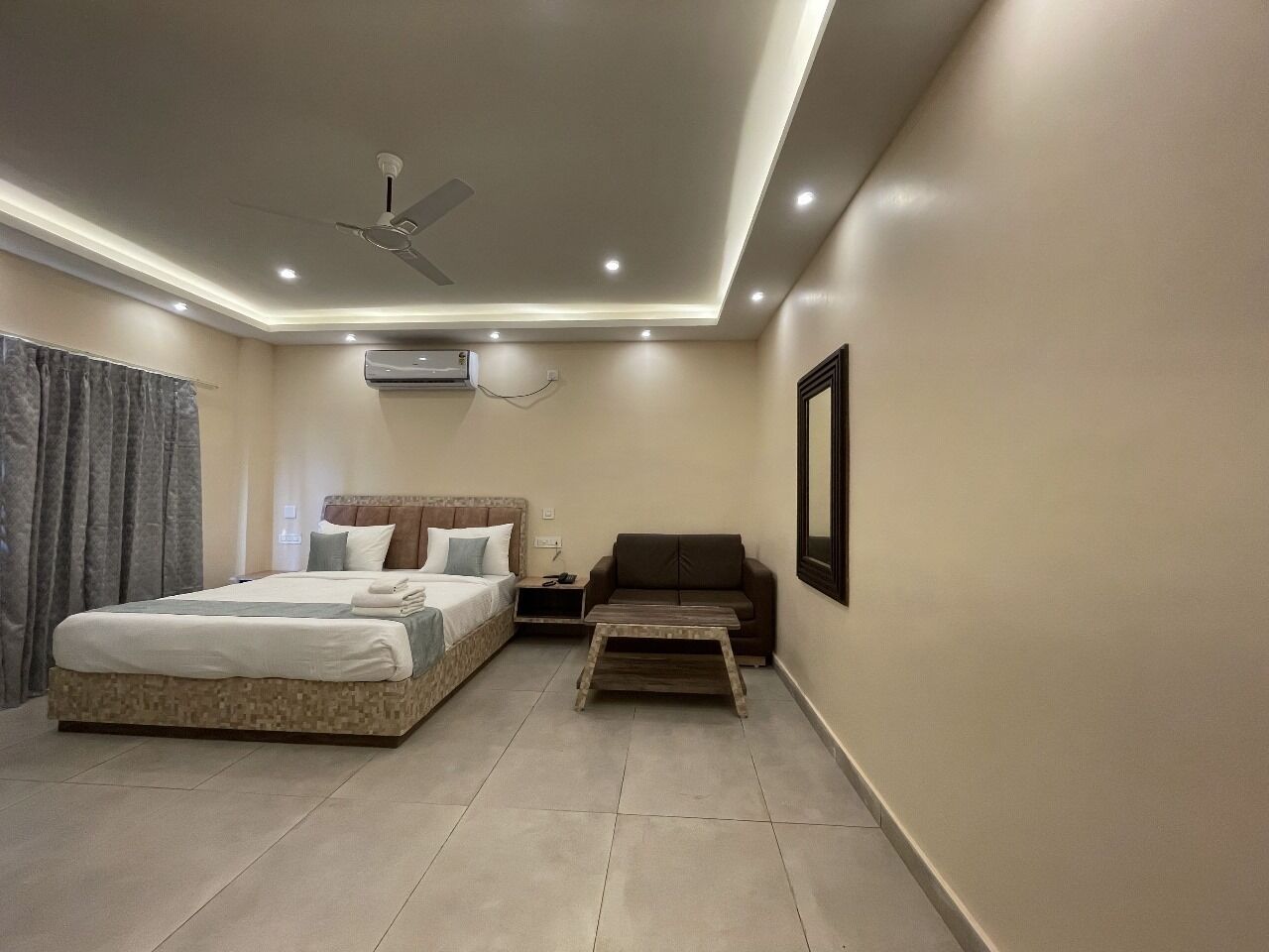A modern bedroom with a bed, a nightstand, a sofa, and a ceiling fan.