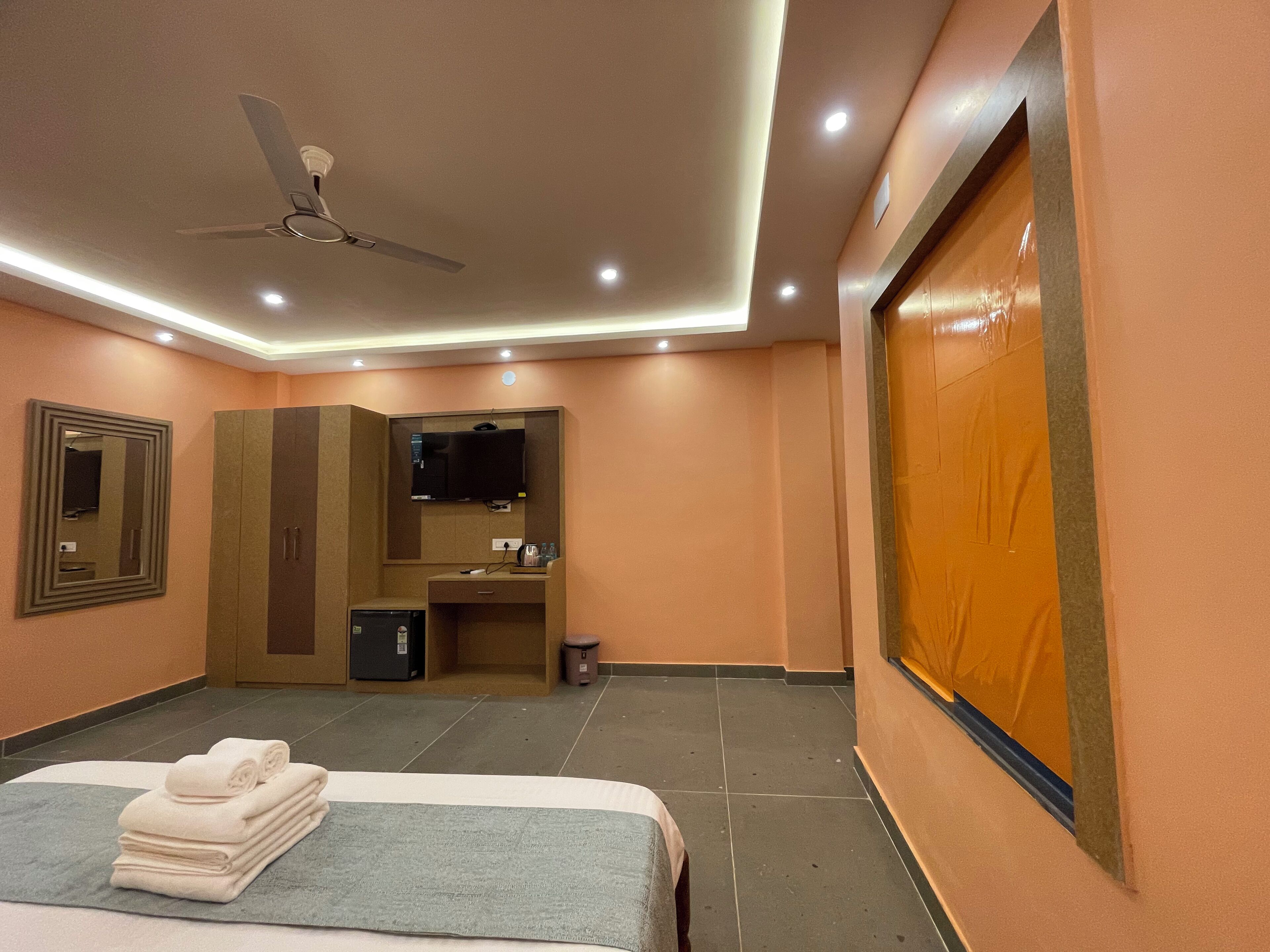 A hotel room with a bed, a desk, a television, a ceiling fan, and a wardrobe.