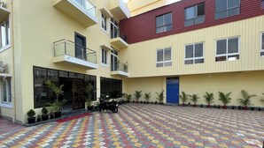 A courtyard with a patterned tiled floor, a motorcycle parked near a building entrance, and potted plants along the walls. - Tiger Inn Beach Resort (Mandarmani)