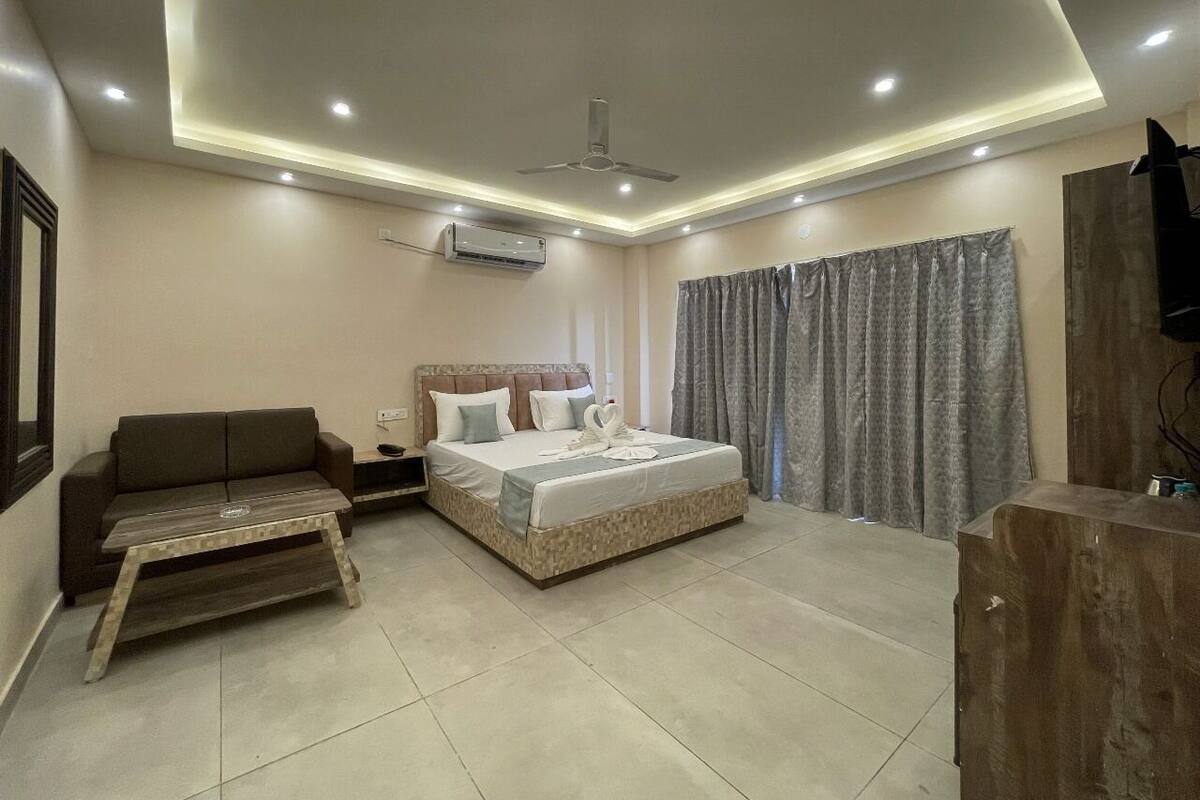 A modern hotel room with a bed, a sofa, a small table, and a TV.