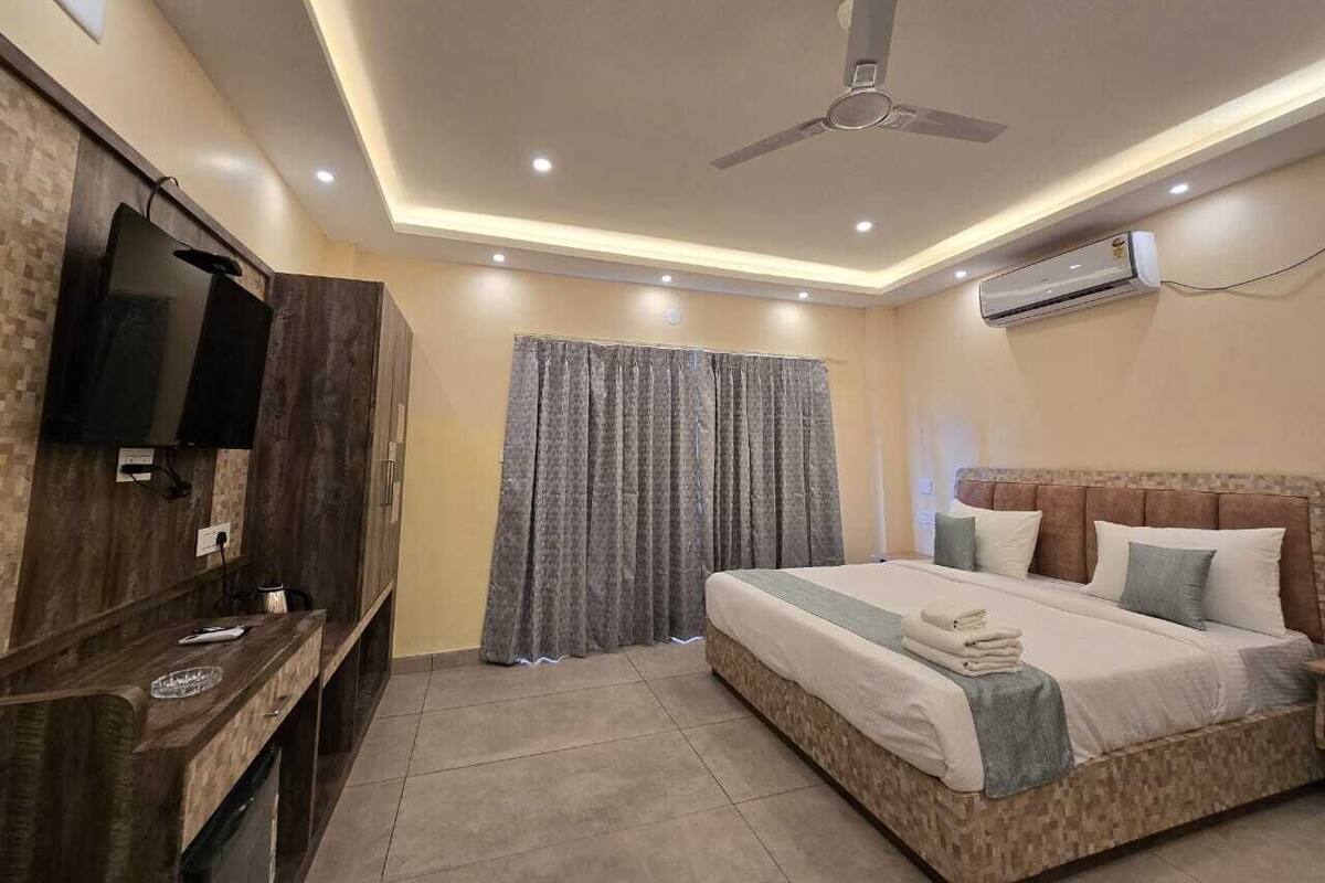 A bedroom with a bed, a TV, a ceiling fan, and an air conditioner.