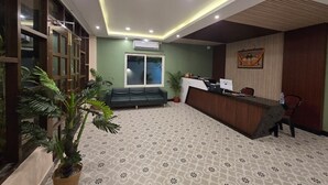 A reception area with a reception desk, seating area, and a large window. - Tiger Inn Beach Resort (Mandarmani)