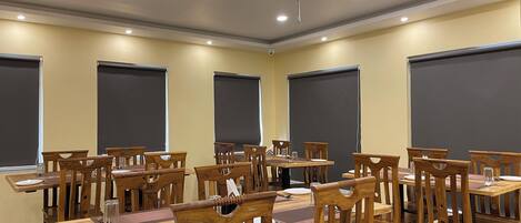 Una sala de conferencias con mesas y sillas de madera, amplias pantallas negras en las paredes e iluminación empotrada en el techo.