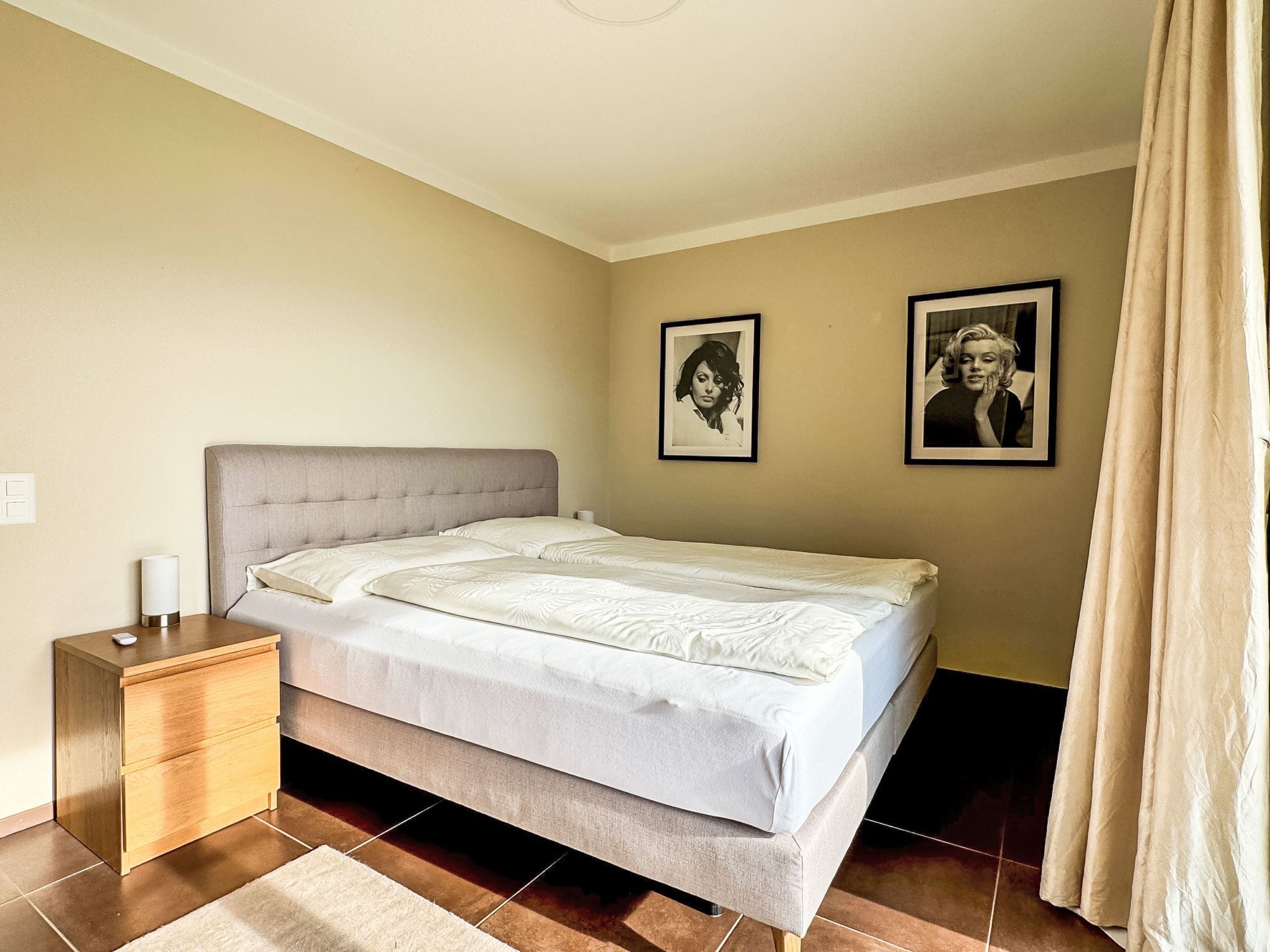 Une chambre à coucher avec un lit, une table de chevet et deux tableaux encadrés accrochés au mur.