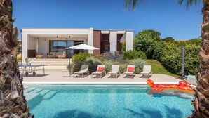 A modern house with a pool, lounge chairs, and a table with chairs. - Villa Grofica, beheizter Pool, Taverne, Strandnähe by Interhome (Pula)