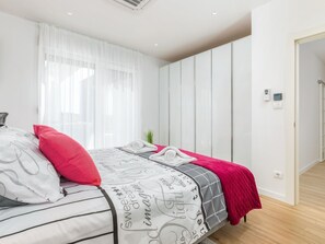 A modern bedroom with a bed, white walls, and a wooden floor. - Villa Grofica, beheizter Pool, Taverne, Strandnähe by Interhome (Pula)
