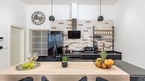 A modern kitchen with a black refrigerator, a microwave, and a coffee machine. There is a wooden dining table with chairs, a fruit bowl, and a potted plant. - Villa Grofica, beheizter Pool, Taverne, Strandnähe by Interhome (Pula)