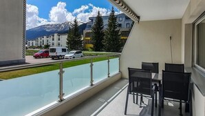 Ein Balkon mit Blick auf einen Berg, eine Straße mit Fahrzeugen und moderne Gebäude.