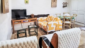 Una sala de estar con televisor, sofá, sillones y una obra de arte en la pared.