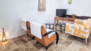 Una sala de estar con un sofá, un televisor, una mesita y obras de arte en las paredes.