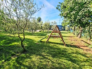 A grassy outdoor area with a wooden swing set and a small tree. - Hacienda Matea - Oase der Romantik in Strandnähe by Interhome (Pula)