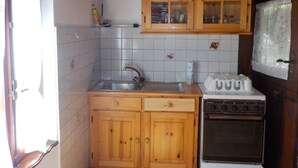 A compact kitchen with wooden cabinets, a sink, and a stove. - Schönes Rustico by Interhome (Dangio – Torre)
