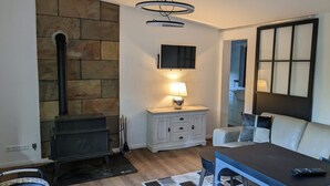 Een moderne woonkamer met een stenen open haard, een flatscreen televisie, een eethoek met een tafel en stoelen, en een groot raam met uitzicht.