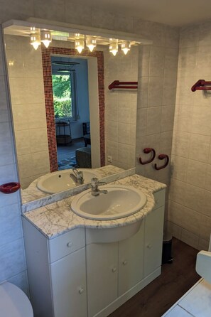 Une salle de bain avec deux lavabos, un grand miroir et un porte-serviettes rouge.