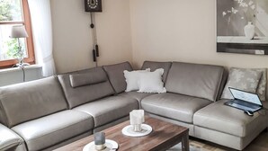 En stue med en sofa, et sofabord, et ur og et billede på væggen.