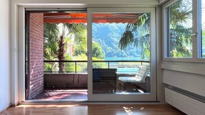 A room with a sliding glass door leading to a balcony with a view of a tropical landscape and a pool. - "Lake Escape", mit Pool by Interhome (MAROGGIA)