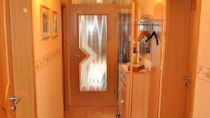 A hallway with wooden doors, a glass door with a curtain, and a small rug on the floor. - Apartment Klein by Interhome (Dickenschied)