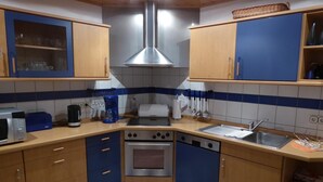 A compact kitchen with wooden cabinets, a stainless steel range hood, a microwave, and a dishwasher. - Apartment Klein by Interhome (Dickenschied)