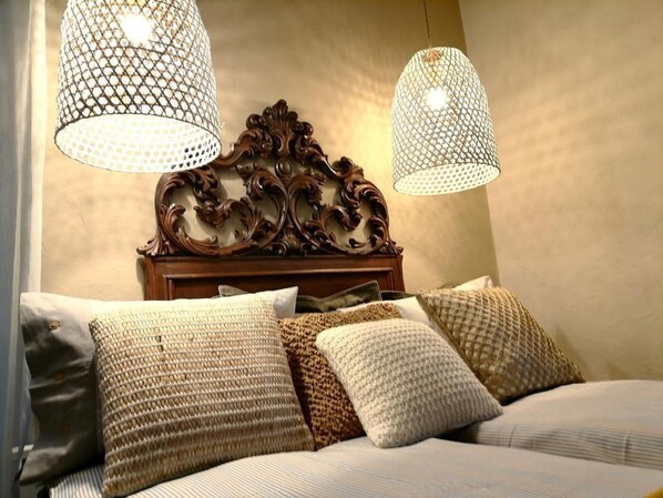 A bed with a headboard, multiple pillows, and two hanging lamps.