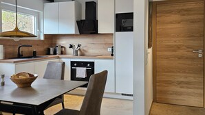 Una cocina moderna con armarios blancos, un refrigerador Bosch y una puerta de madera.