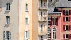Um edifício com vários andares, varandas, um pátio e montanhas ao fundo.