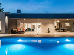 A modern outdoor pool area with a patio, seating, and a view of the interior. - Villa Sanivaro mit beheiztem Pool und Whirlpool by Interhome (Bokordici)