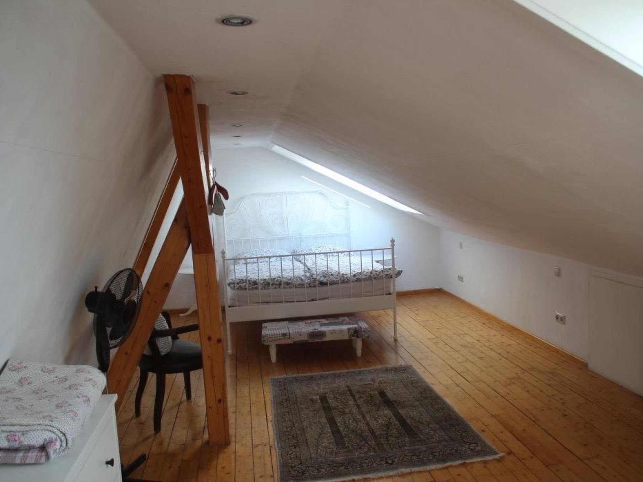 A small attic bedroom with a bunk bed, a desk, and a chair.