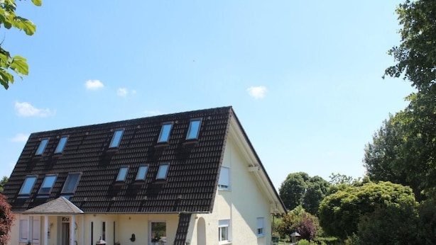 Un bâtiment à deux étages, doté d’un toit en pente, de nombreuses fenêtres et d’une allée pavée.