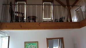 Une pièce avec un balcon en bois, un tableau au mur et une fenêtre donnant sur un beau paysage.