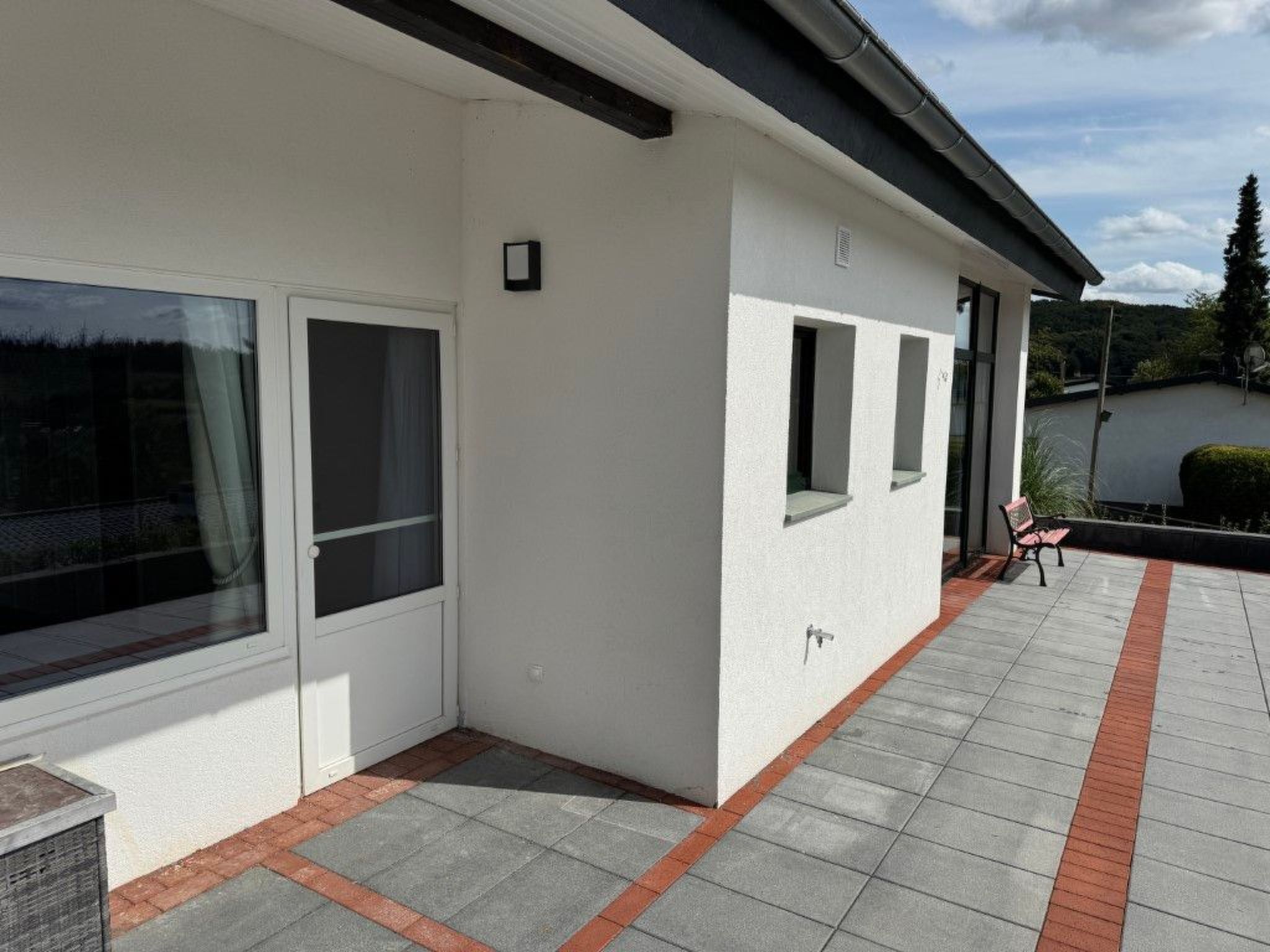 Un bâtiment moderne doté de grandes fenêtres et d’une terrasse carrelée.