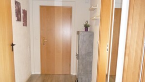 A hallway with wooden flooring, a closed door, a small refrigerator, and a potted plant. - Apartment mit Hund by Interhome (Bodenwerder)
