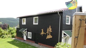 A black building with white trim, a small door, and windows. - Premium-Ferienwohnung mit Bergblick im Haus Hopfe by Interhome (Goslar)
