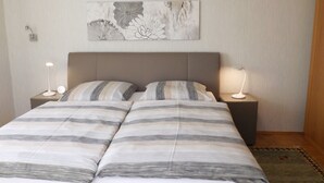 A double bed with striped bedding, two bedside tables with lamps, and a wall-mounted abstract art piece. - Premium-Ferienwohnung mit Bergblick im Haus Hopfe by Interhome (Goslar)