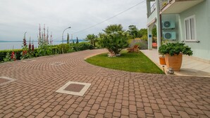 A paved pathway leading to a building with a balcony, surrounded by greenery and a view of the sea. - Wohnung mit Terrasse by Interhome (Opatija)