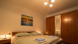 A bedroom with a large bed, wooden wardrobe, and a painting on the wall. - Wohnung mit Terrasse by Interhome (Opatija)