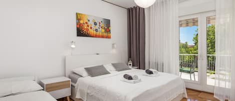 A modern bedroom with a large bed, a smaller bed, a painting, and a balcony with curtains.